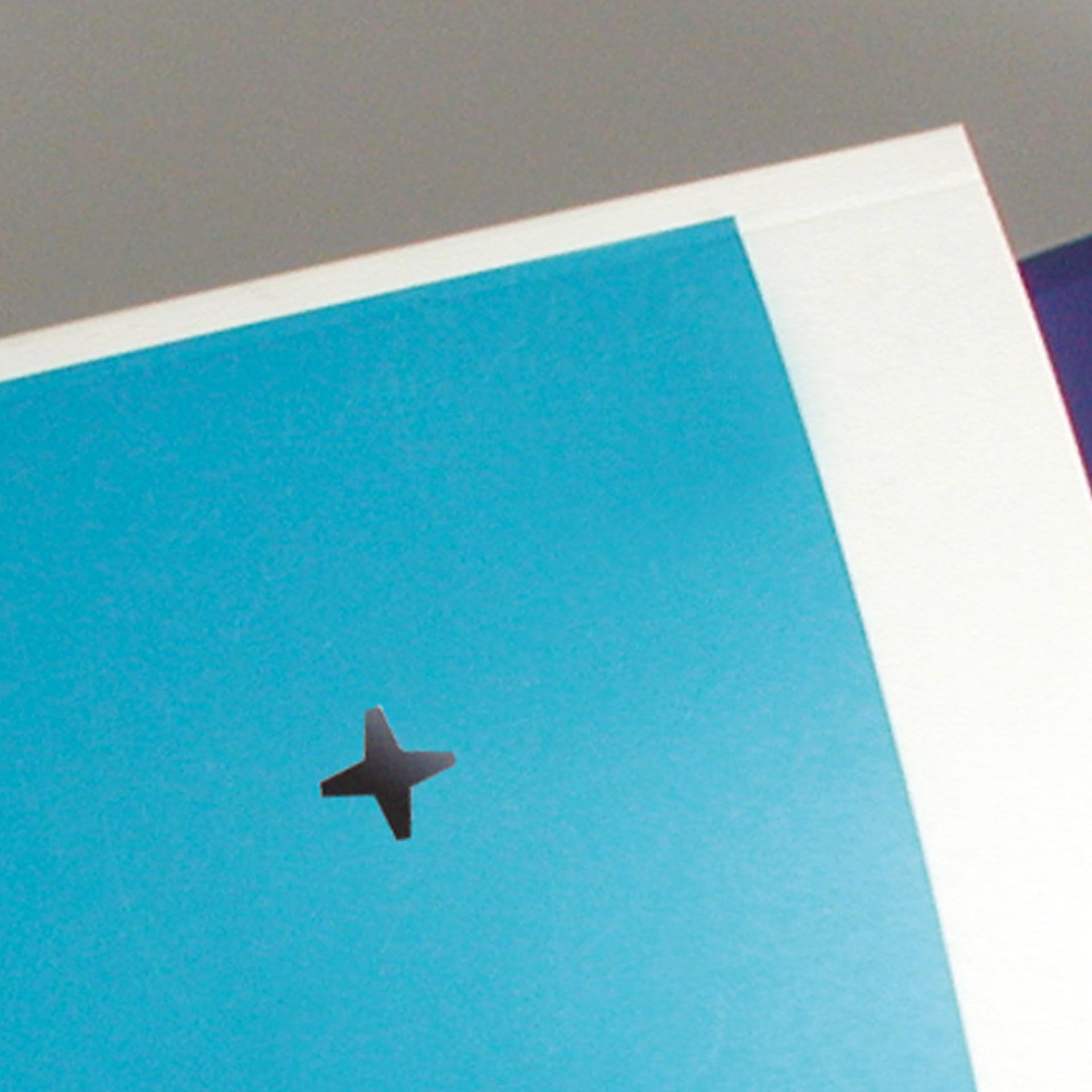 Beispiel einer Lochstanzung im Papier Detailansicht eines Papierblatts mit einer ausgestanzten Lochmarkierung in Kreuzform. Das Lochzeichen ist mittig in einem blauen Druckbereich des Dokuments sichtbar.