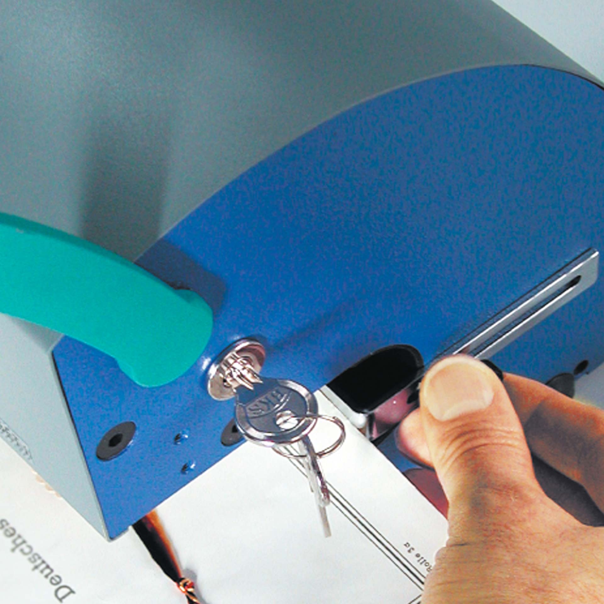 PERNUMA PERFOSET I/P & II/P Detailansicht Einfuhröffnung und Schloss Detailansicht eines PERNUMA PERFOSET I/P & II/P Prägegeräts mit eingesetztem Schlüssel im Schloss, während ein Dokument in die Einfuhröffnung geschoben wird.