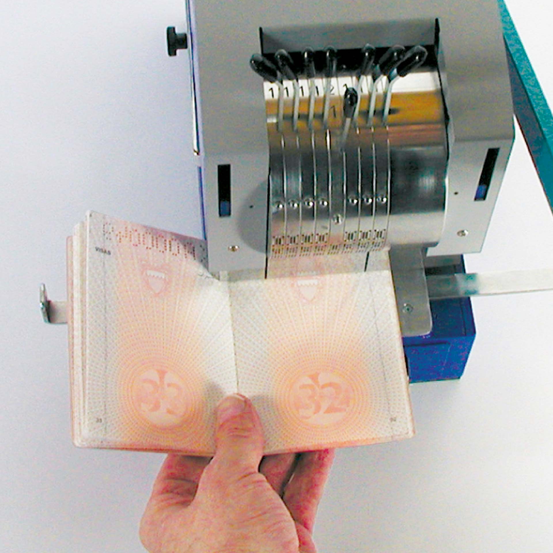 PERNUMA PERFOSTAR Perforiermaschine Anwendungsbeispiel PERNUMA PERFOSTAR Perforiermaschine im Einsatz, Hand führt ein Dokument in die Maschine ein, während das Räderwerk sichtbar ist.