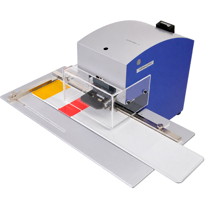 Beispielbild: PERNUMA METALLPRINT E Prägen eines Schildes Elektrische Prägemaschine PERNUMA METALLPRINT E mit Anlegetisch und transparentem Schutzgehäuse beim Prägen eines Schildes, Beispielanwendung