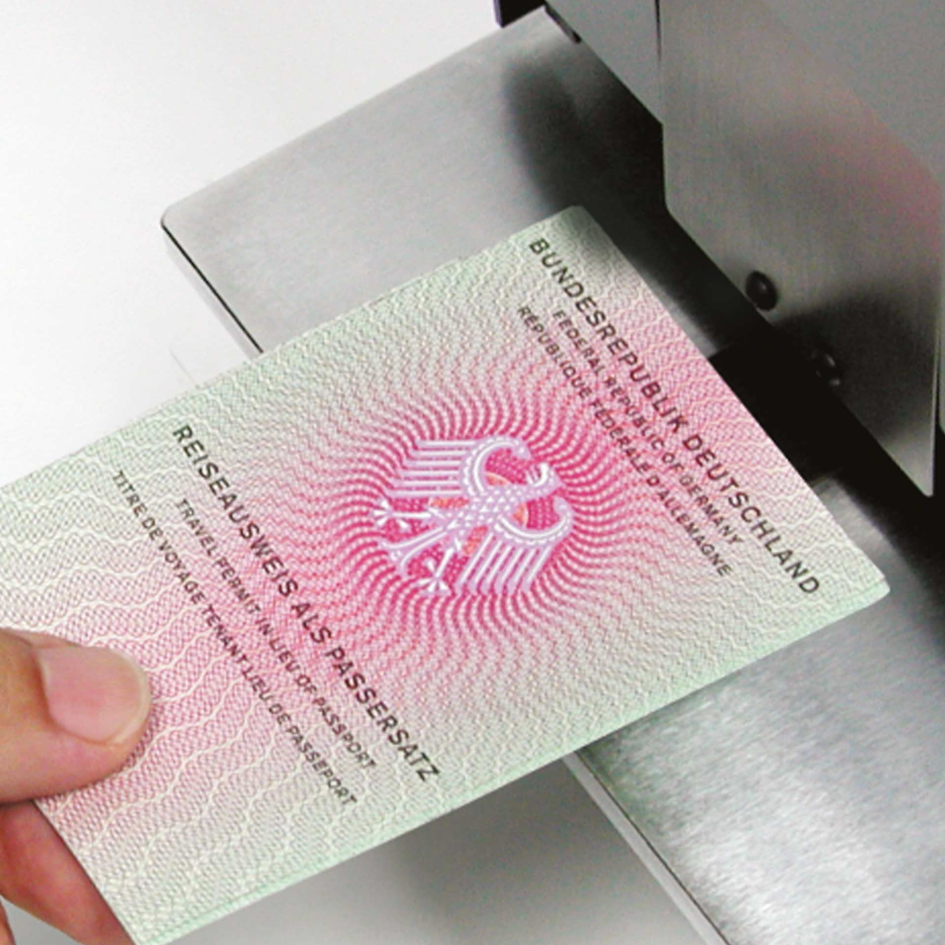 PERNUMA OFFICE L Einfuhrbereich mit Dokument Anwendung Detailansicht der Einfuhröffnung der PERNUMA OFFICE L Loch-Entwertungsmaschine. Eine Hand führt ein Dokument mit der Aufschrift „Reiseausweisersatz“ in den Einfuhrbereich auf der Metallauflage.