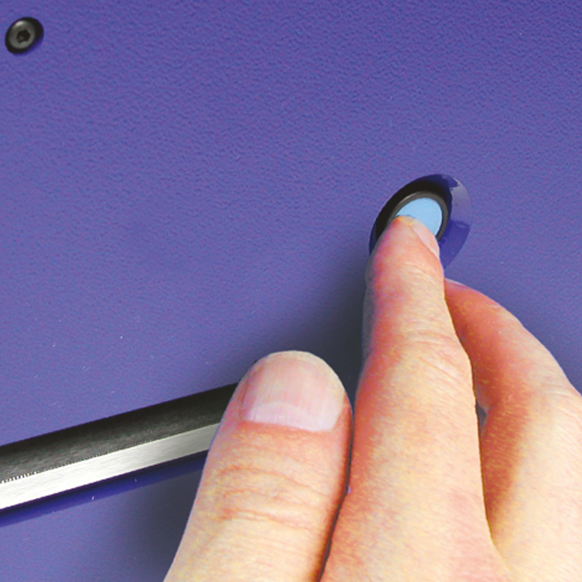 PERNUMA OFFICE L Druckknopf zur Auslösung des Stanzvorgangs Detailansicht der PERNUMA OFFICE L Loch-Entwertungsmaschine. Eine Hand drückt den seitlich angebrachten runden Druckknopf zum Auslösen des Stanzvorgangs.