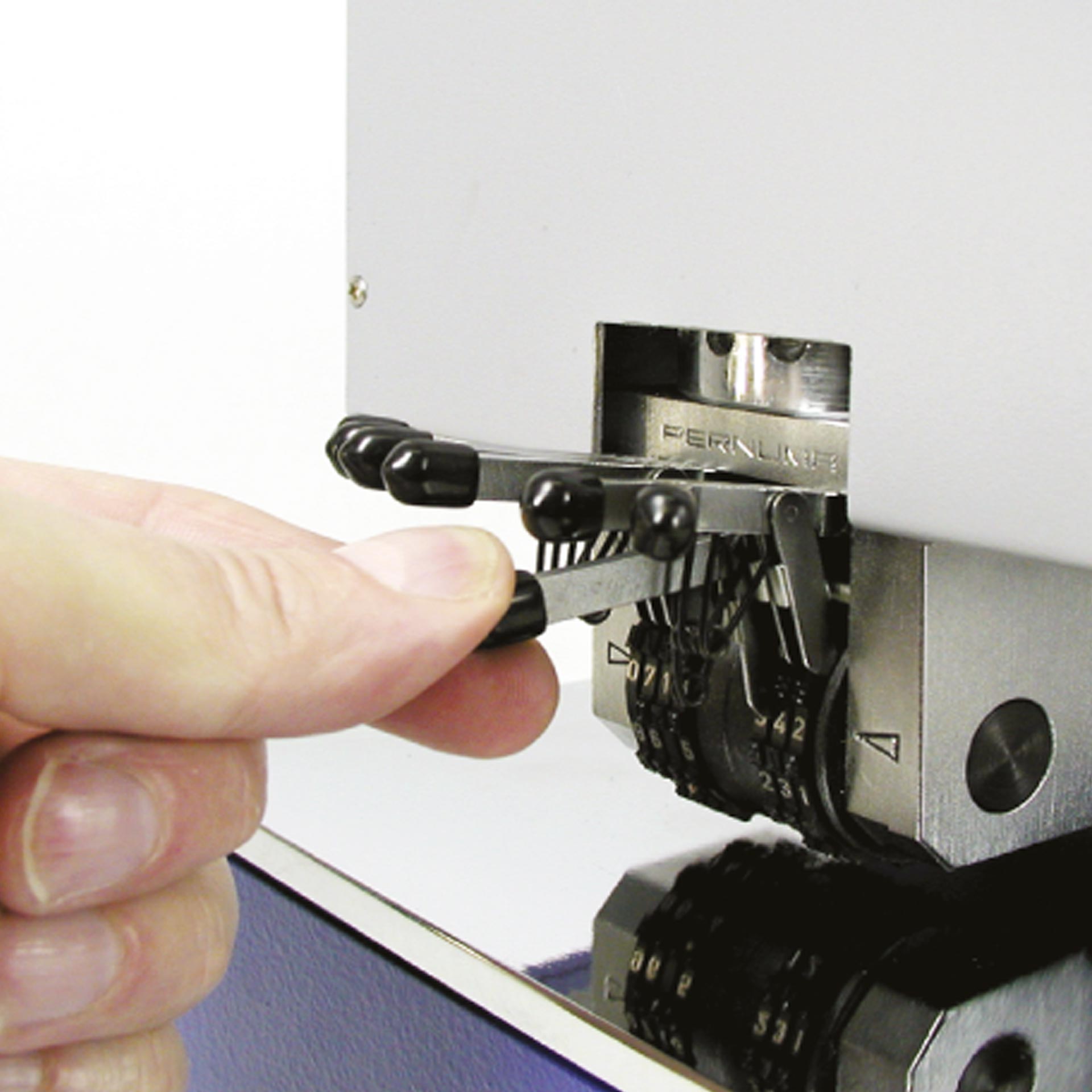 PERNUMA METALLPRINT I Einstellung Prägeeinheit Detailansicht einer Hand, die einen Einstellhebel an der Prägeeinheit mit Zahlenrädern des PERNUMA METALLPRINT I betätigt