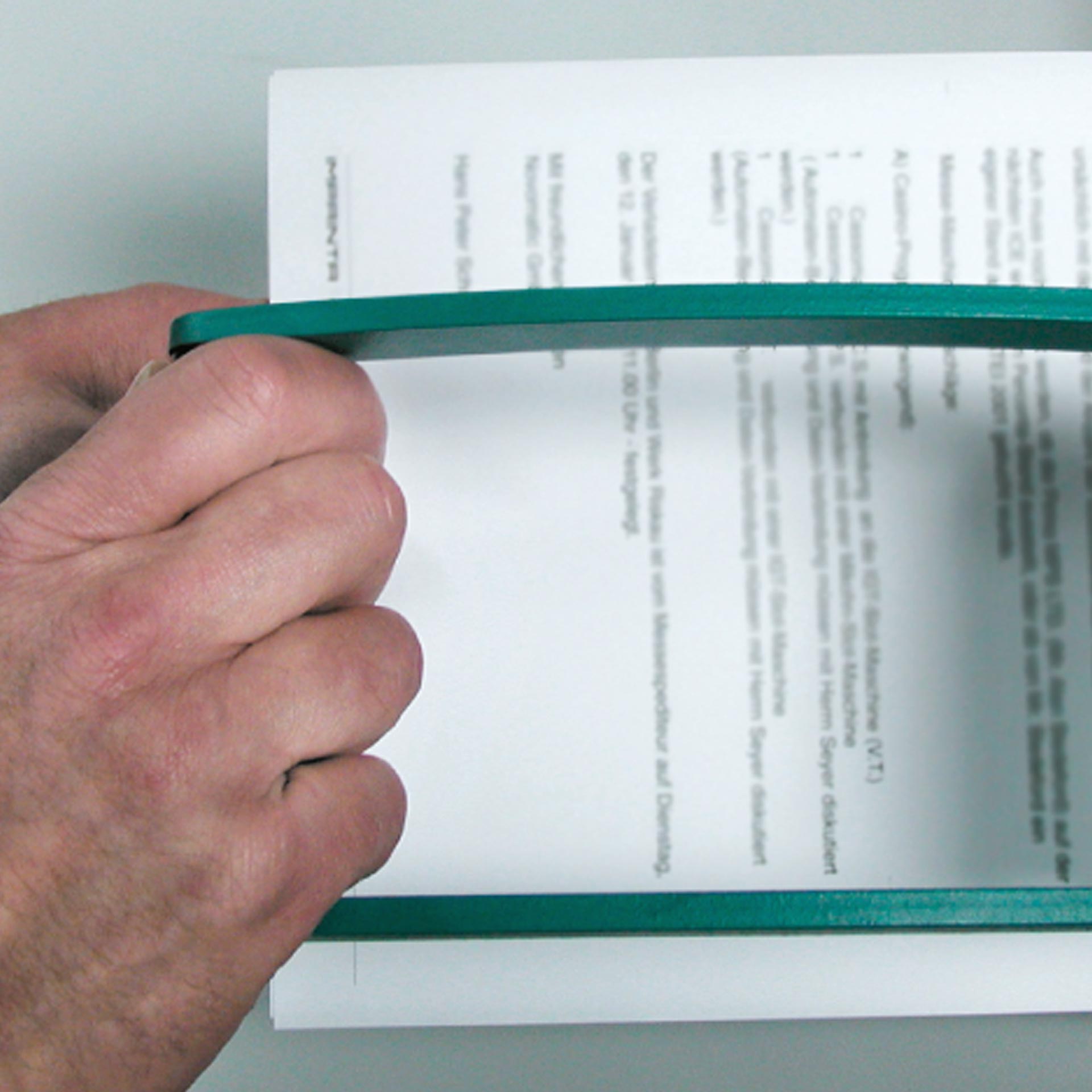 PERNUMA PERFOSET Anwendung Detailansicht Detailansicht eines Hebelgriffs eines PERNUMA PERFOSET Perforiergeräts, der von Hand gehalten wird, mit eingelegtem Dokument im Hintergrund.