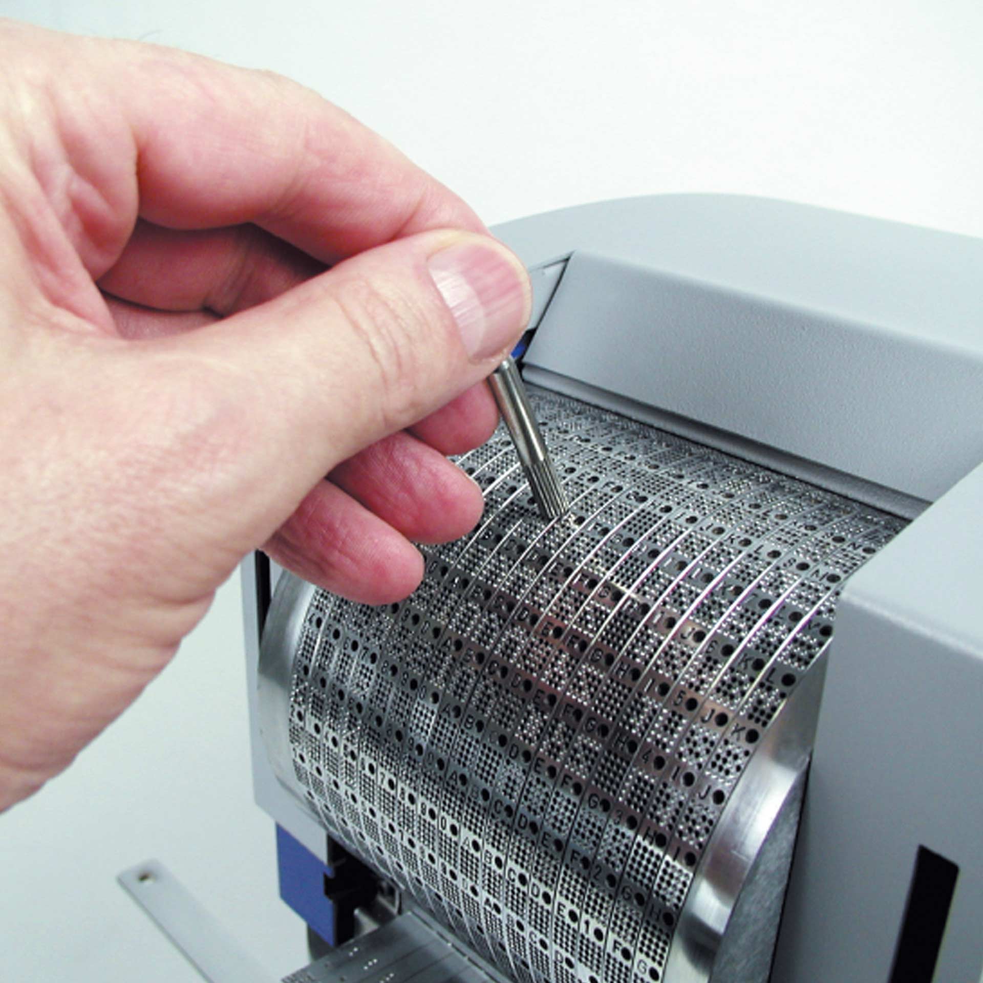 PERNUMA PERFOSTAR ES Perforiermaschine Detail Detailansicht der PERNUMA PERFOSTAR ES Perforiermaschine, Hand stellt mit einem Stift die Zeichenräder ein