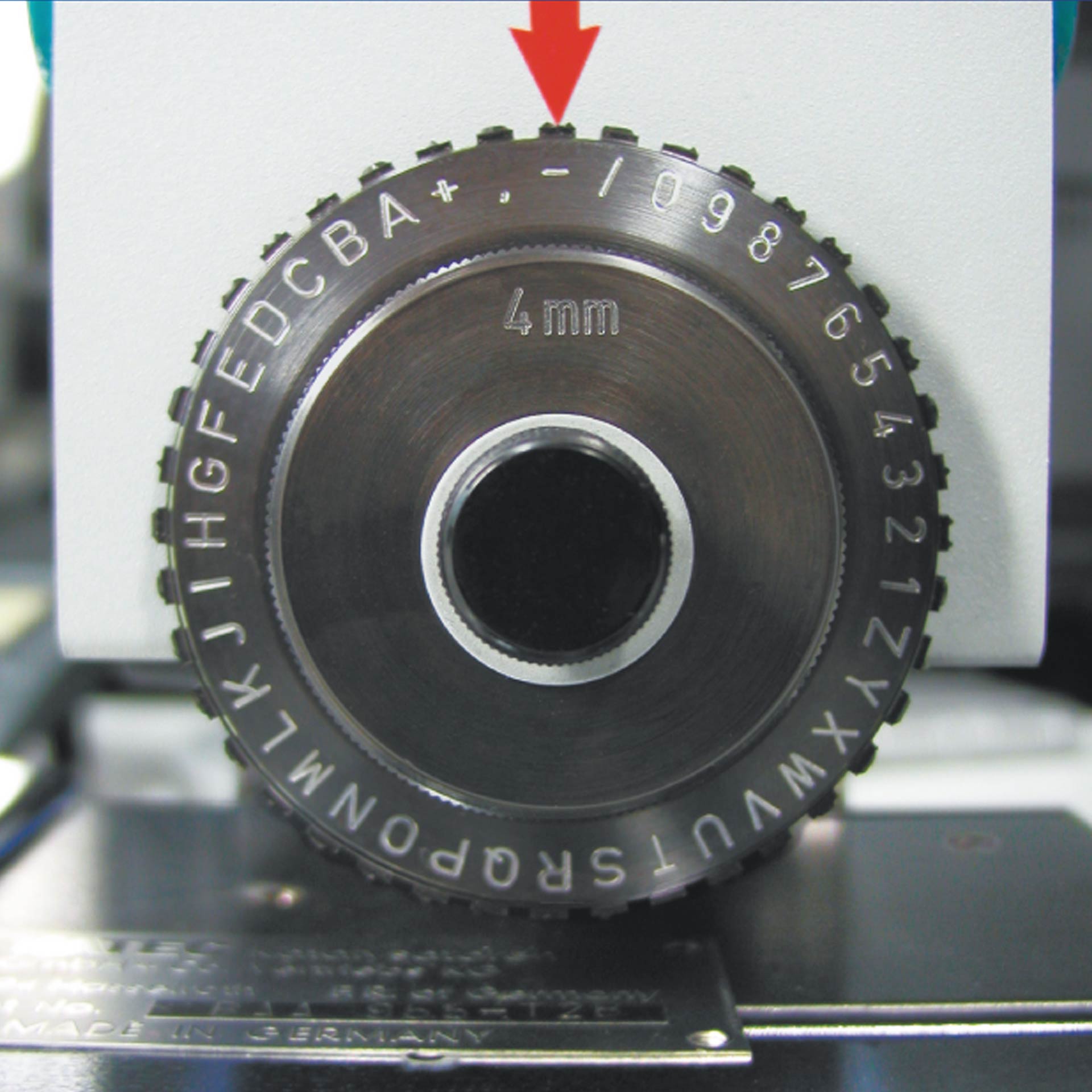 PERNUMA METALLPRINT SP II Metallprägemaschine Typen Detailansicht eines Prägerads mit eingeprägten Buchstaben, Zahlen und Sonderzeichen sowie Markierungspfeil zur Auswahlposition an einem PERNUMA METALLPRINT SP I und SP II.