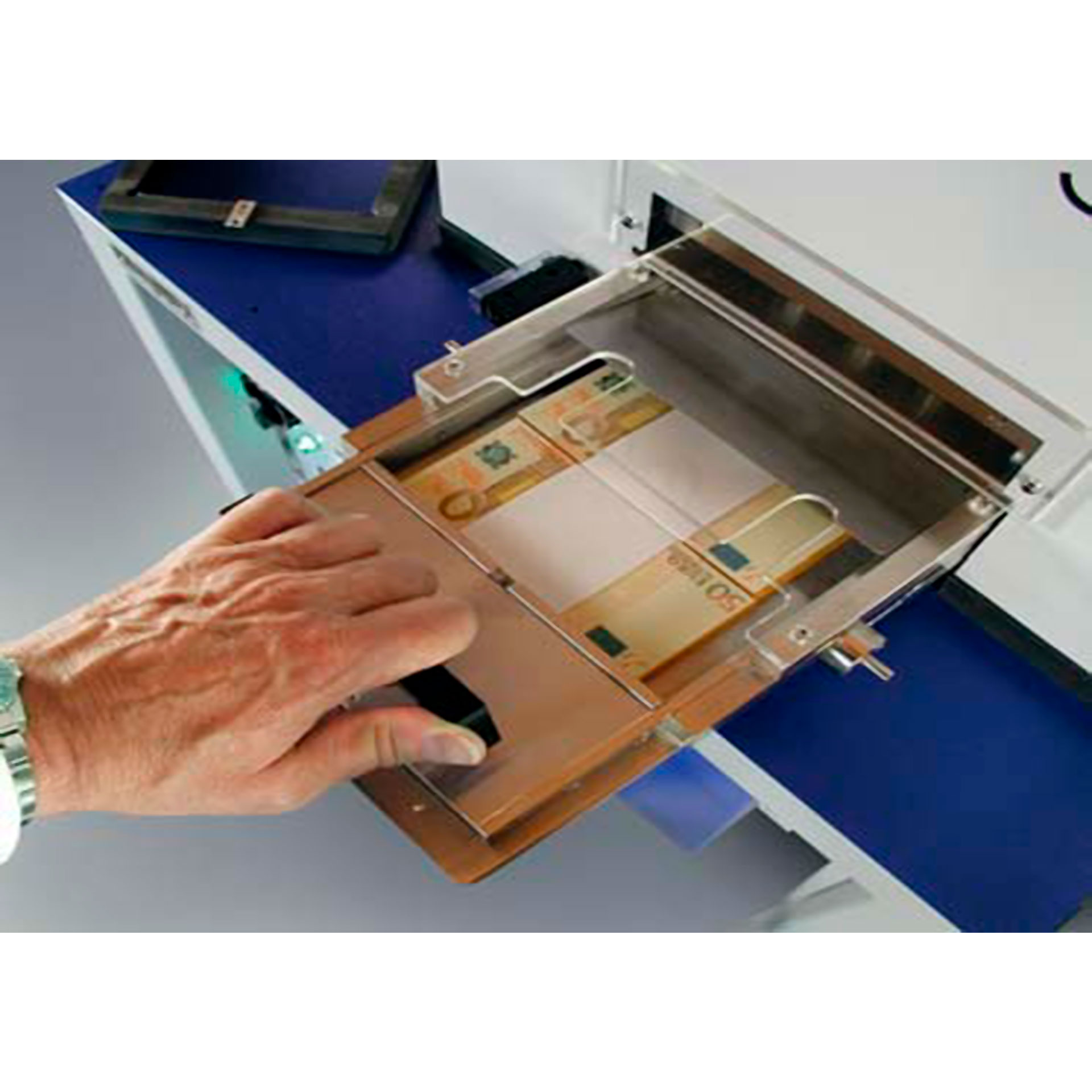 BANKOSTAR Anwendungsbeispiel mit Banknotenbündeln Hand schiebt zwei Bündel Banknoten in den Arbeitsbereich der BANKOSTAR Banknoten-Entwertungsmaschine.